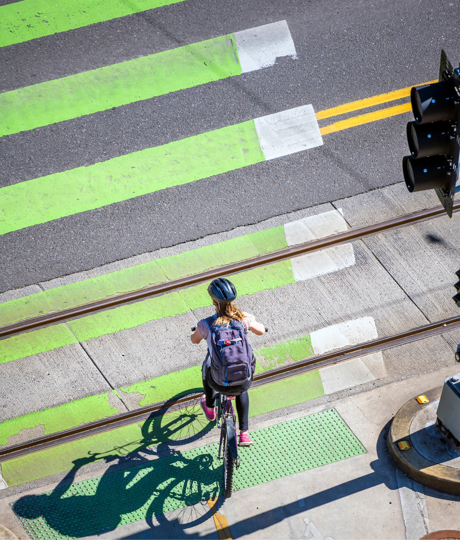 Slender girl on a bike rides across the road along green lane for cyclists allocated at the pedestrian crossing preferring an active healthy lifestyle using cycling as an alternative transportation