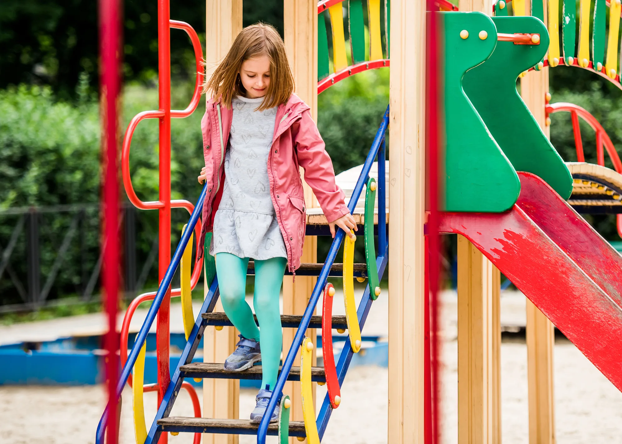 A girl playing on a jungle gym at a public playground